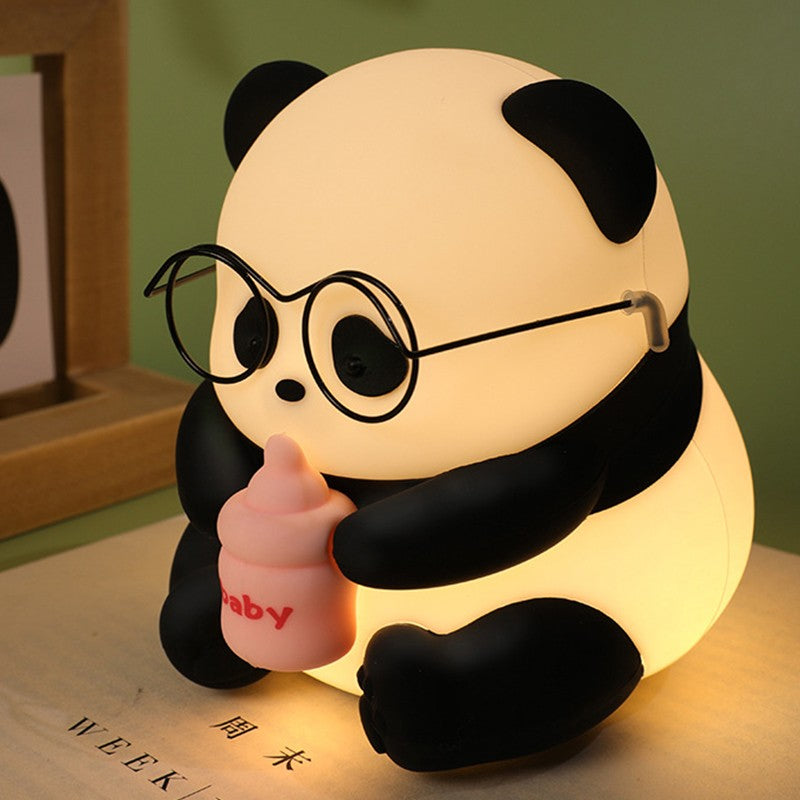 Adicione um toque de fofura e funcionalidade ao seu espaço com a encantadora Luminária Pandinha de Óculos. Feita de silicone macio e durável, esta luminária LED oferece uma iluminação suave e aconchegante. Com uma bateria recarregável integrada, é perfeita para qualquer ambiente, seja como luz noturna no quarto das crianças ou como um adorável destaque decorativo em sua sala de estar.